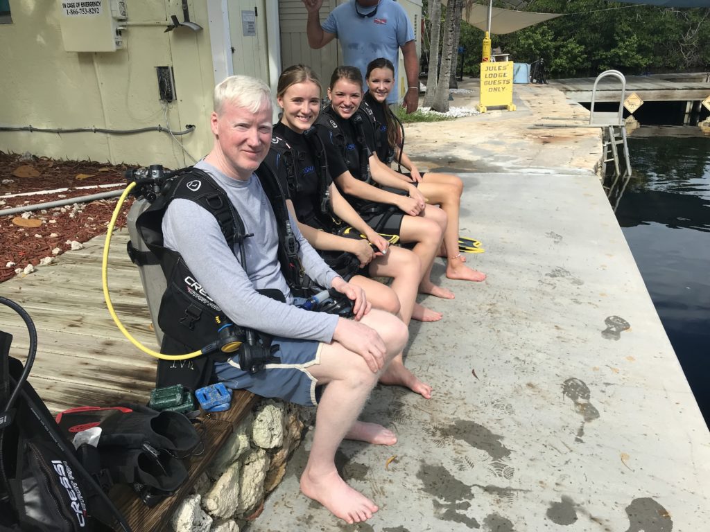 Student divers getting prepared to enter water sat on the side of a lagoon